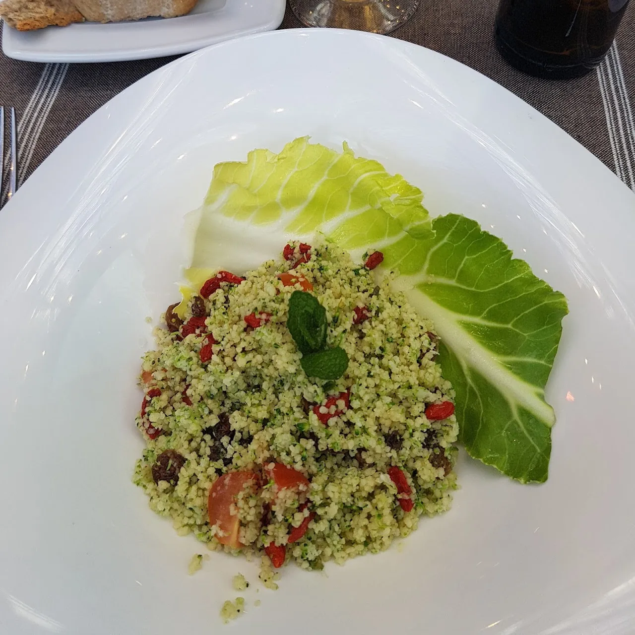 A couscous salad with pomegranate seeds and herbs on a cabbage leaf