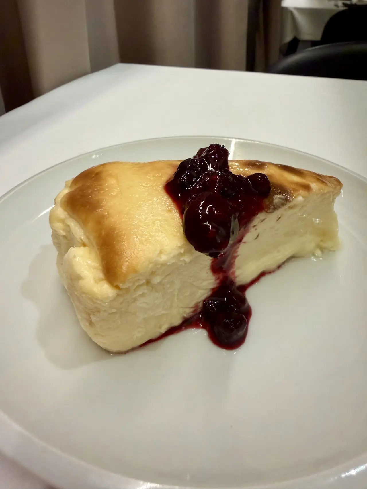 Slice of baked cheesecake with a berry compote drizzle