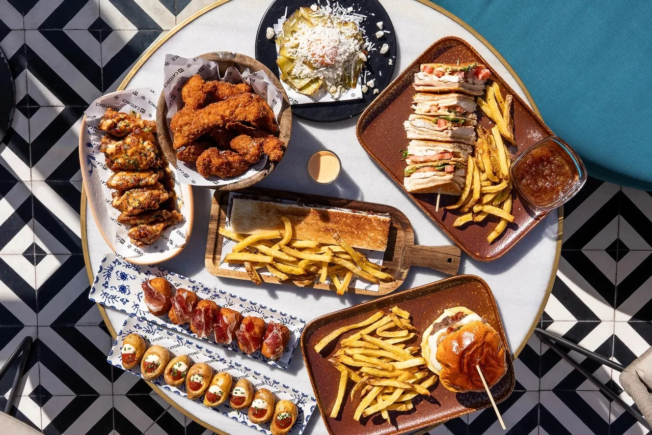 An overhead spread of small plates, fries and fried dishes on a patterned tabletop