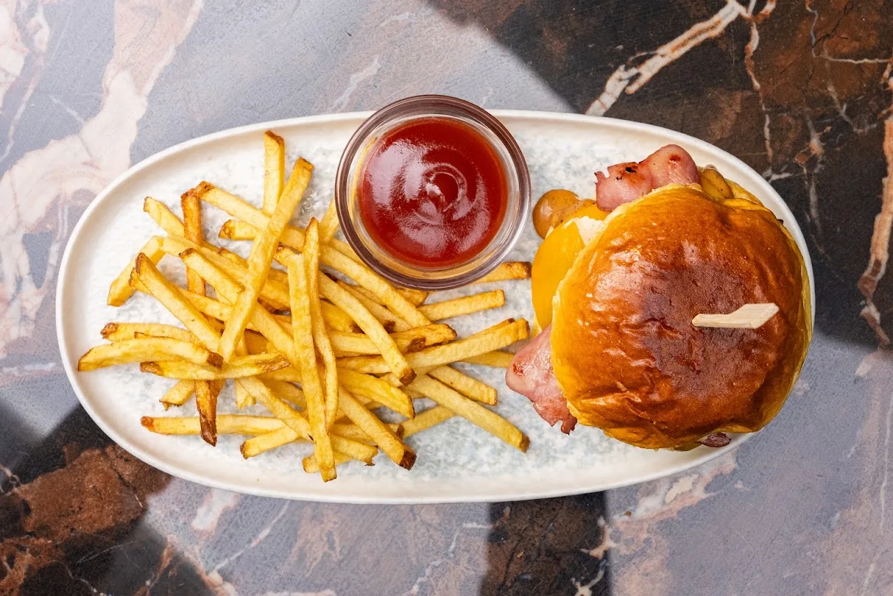 A plate of french fries, ketchup, and a bread roll