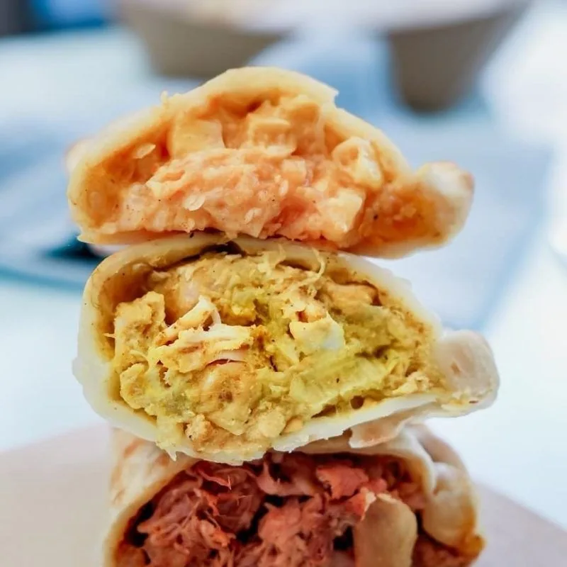 Three stacked halves of empanadas showing different fillings