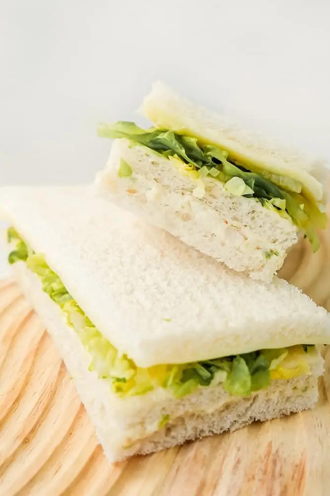 Argentine crustless sandwiches de miga with lettuce and cheese, stacked on a wooden board