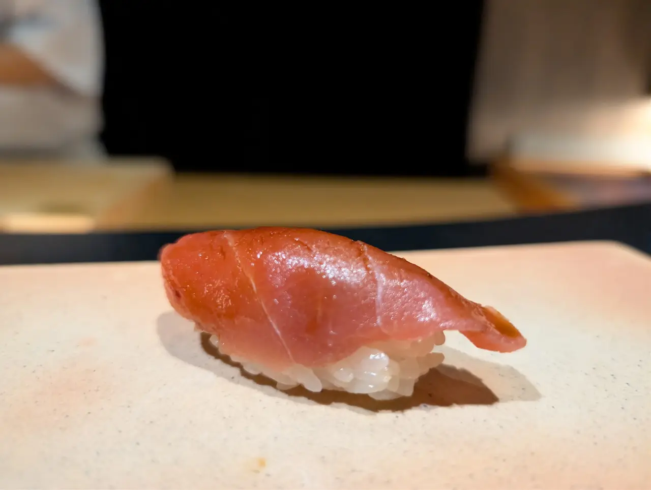 Single piece of tuna nigiri sushi on a counter
