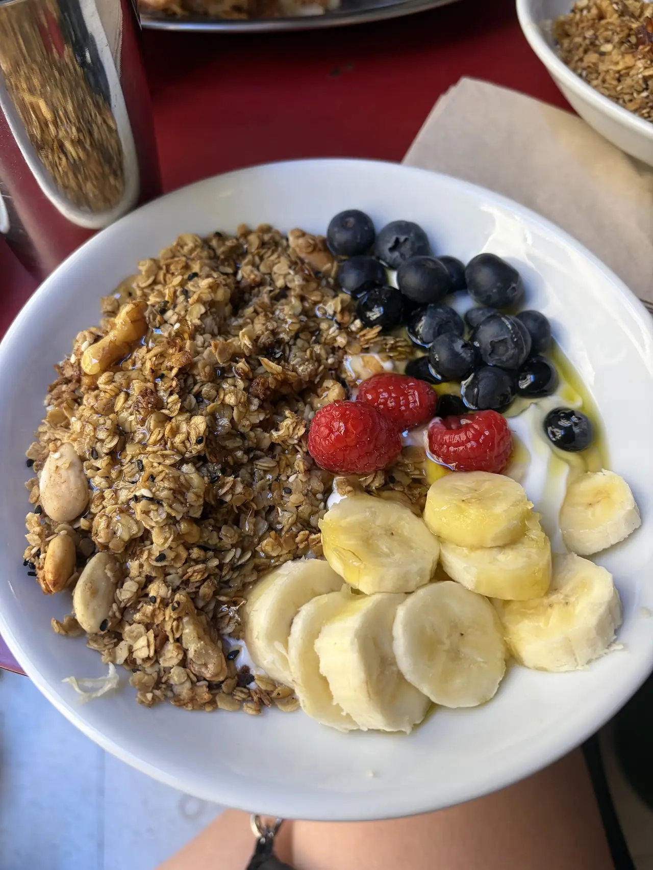 Bowl of granola topped with banana slices and mixed berries.
