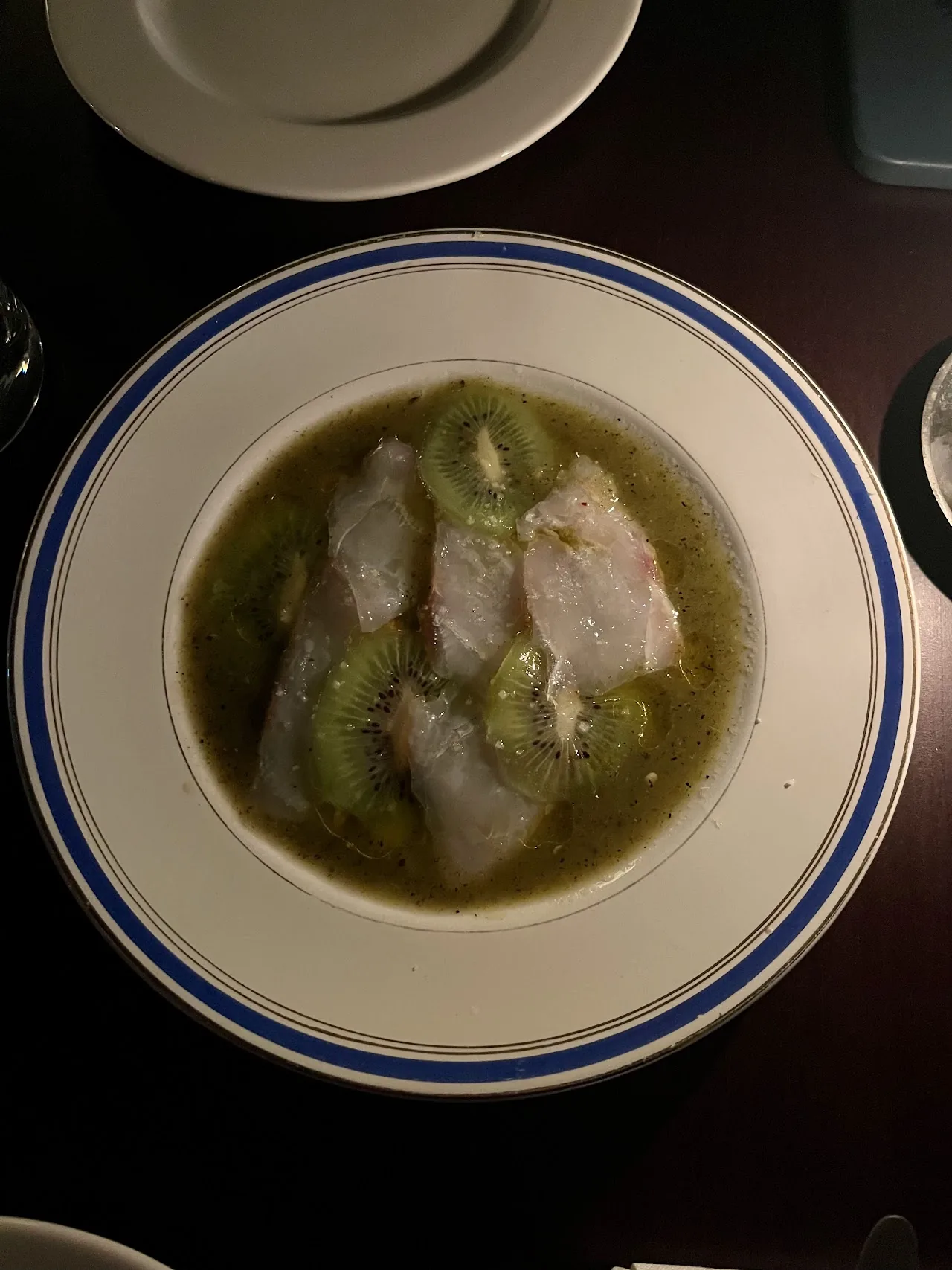 Fish fillets in a green herb broth on a blue-rimmed plate