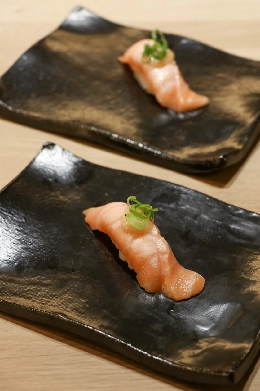 Two pieces of nigiri on black slate plates