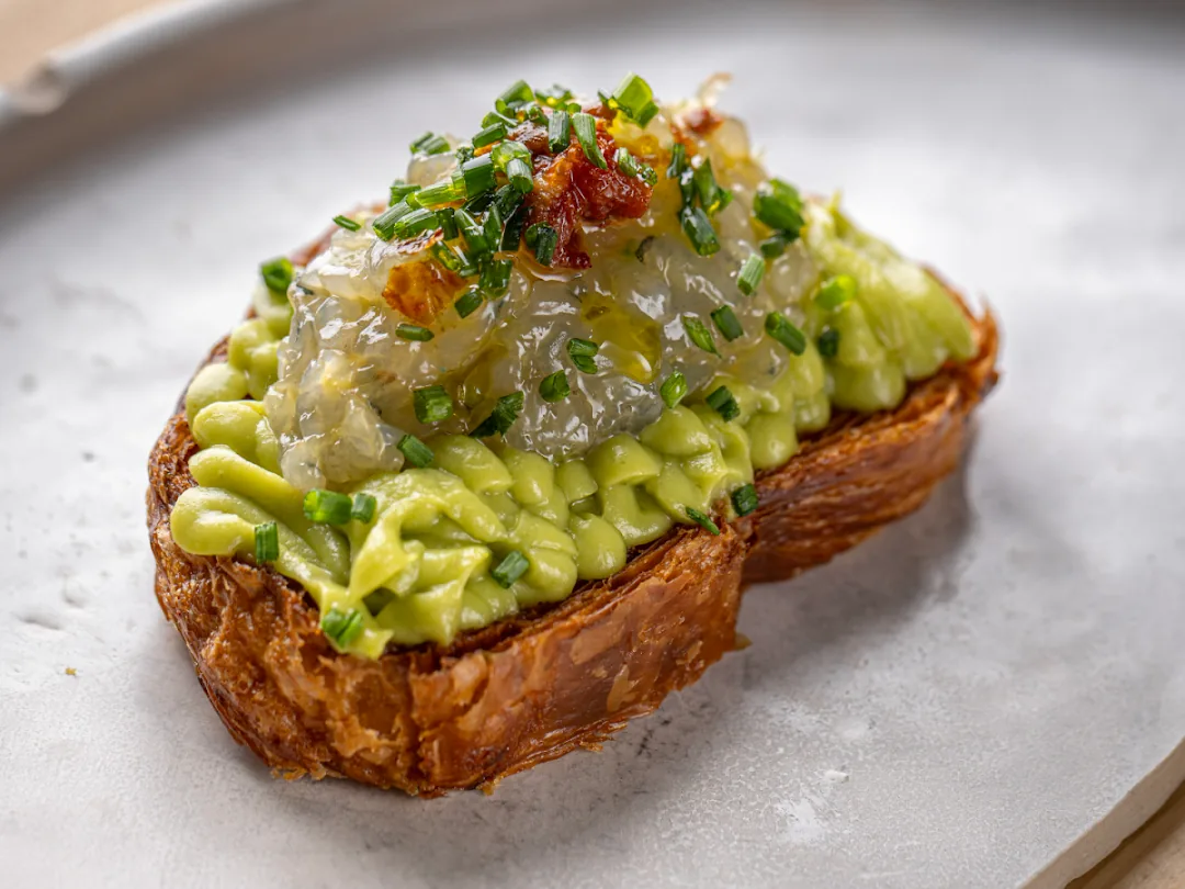Toasted brioche topped with avocado cream, a seafood tartare, and chopped chives