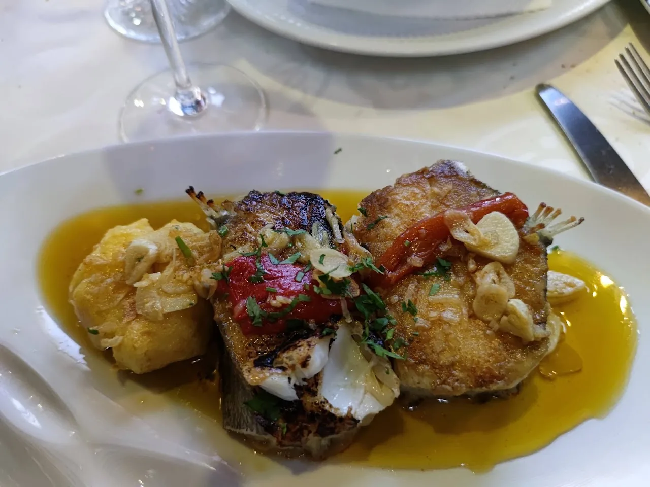 A plated fish fillet with tomato and garlic sauce