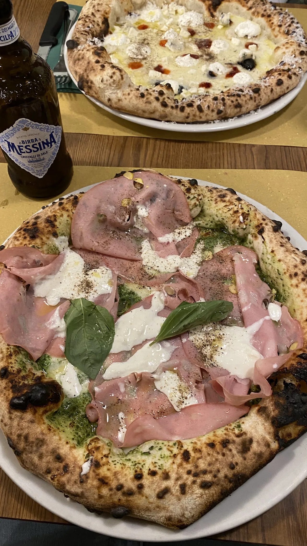 A pizza topped with ham, cheese, and greens
