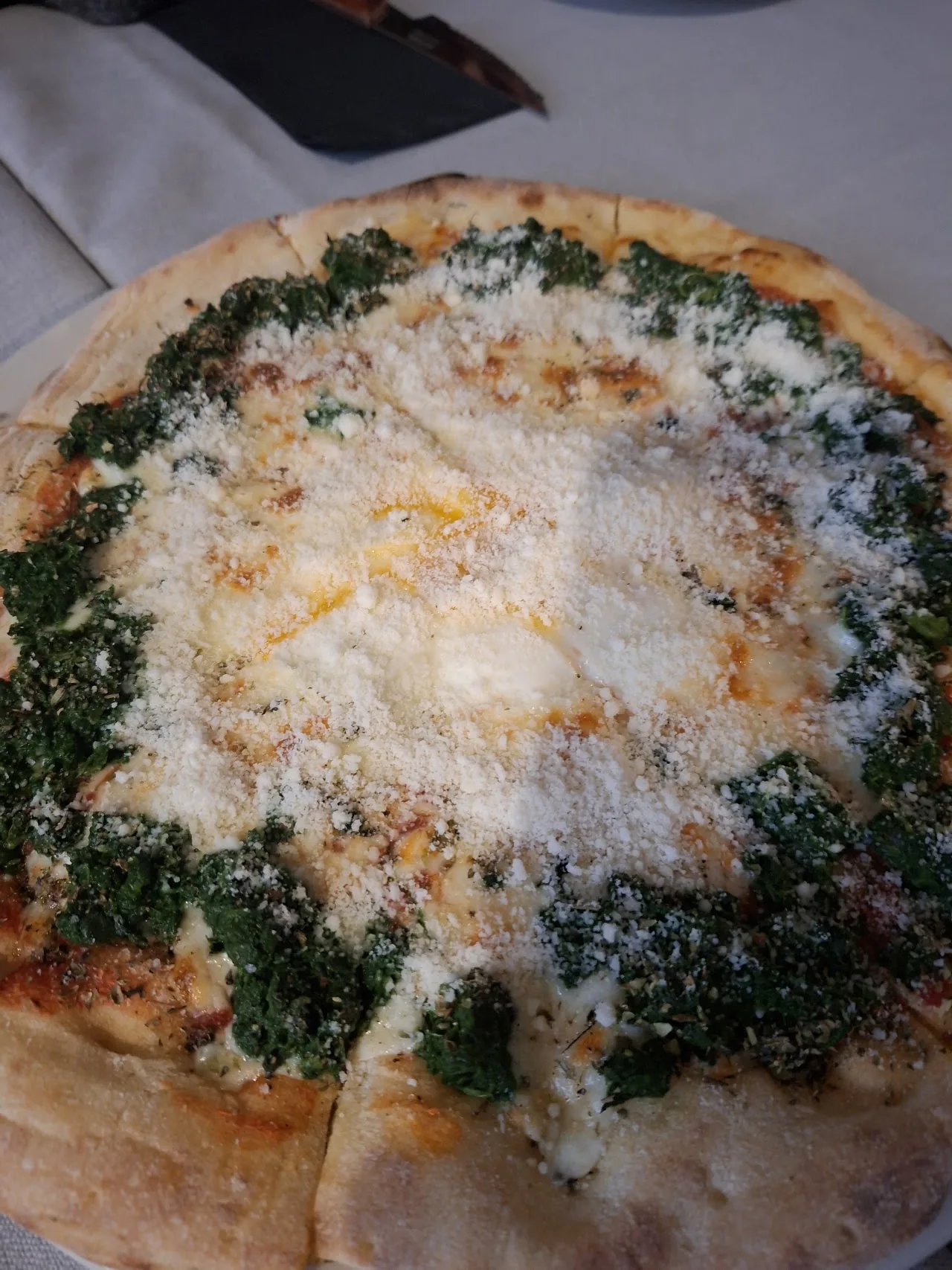 A pizza topped with greens and shredded parmesan