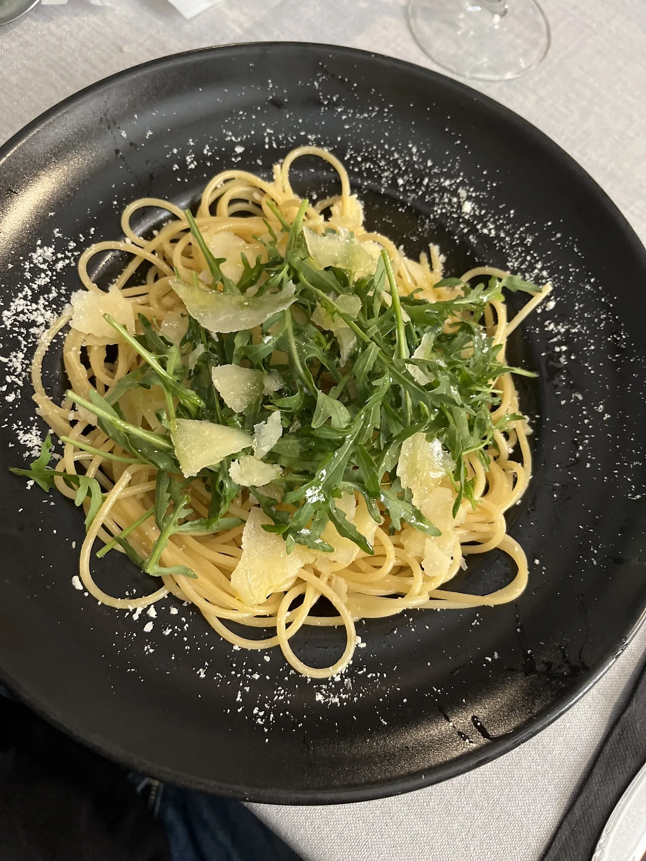 A plate of spaghetti tossed with arugula and shaved parmesan