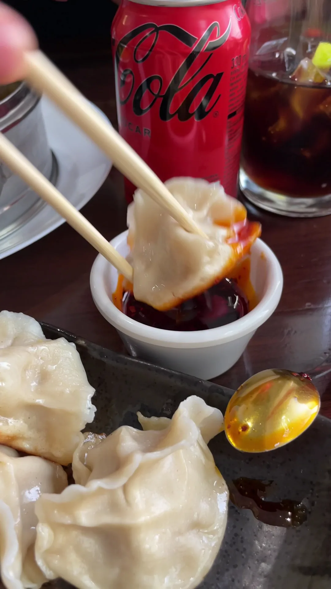 Dumplings held with chopsticks dipped in dark sauce