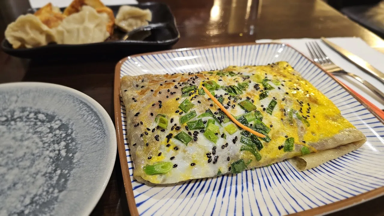 A savory egg crepe topped with scallions and sesame seeds
