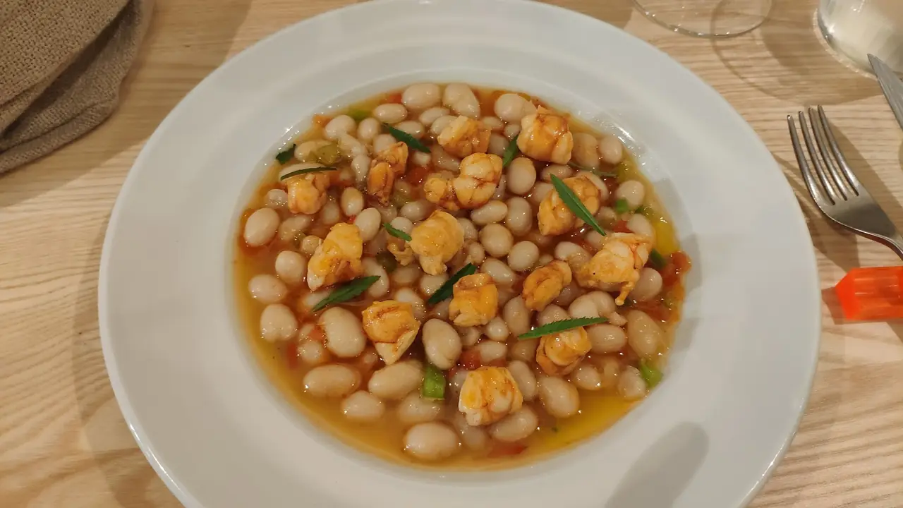 White beans with prawns in a tomato broth served in a white bowl