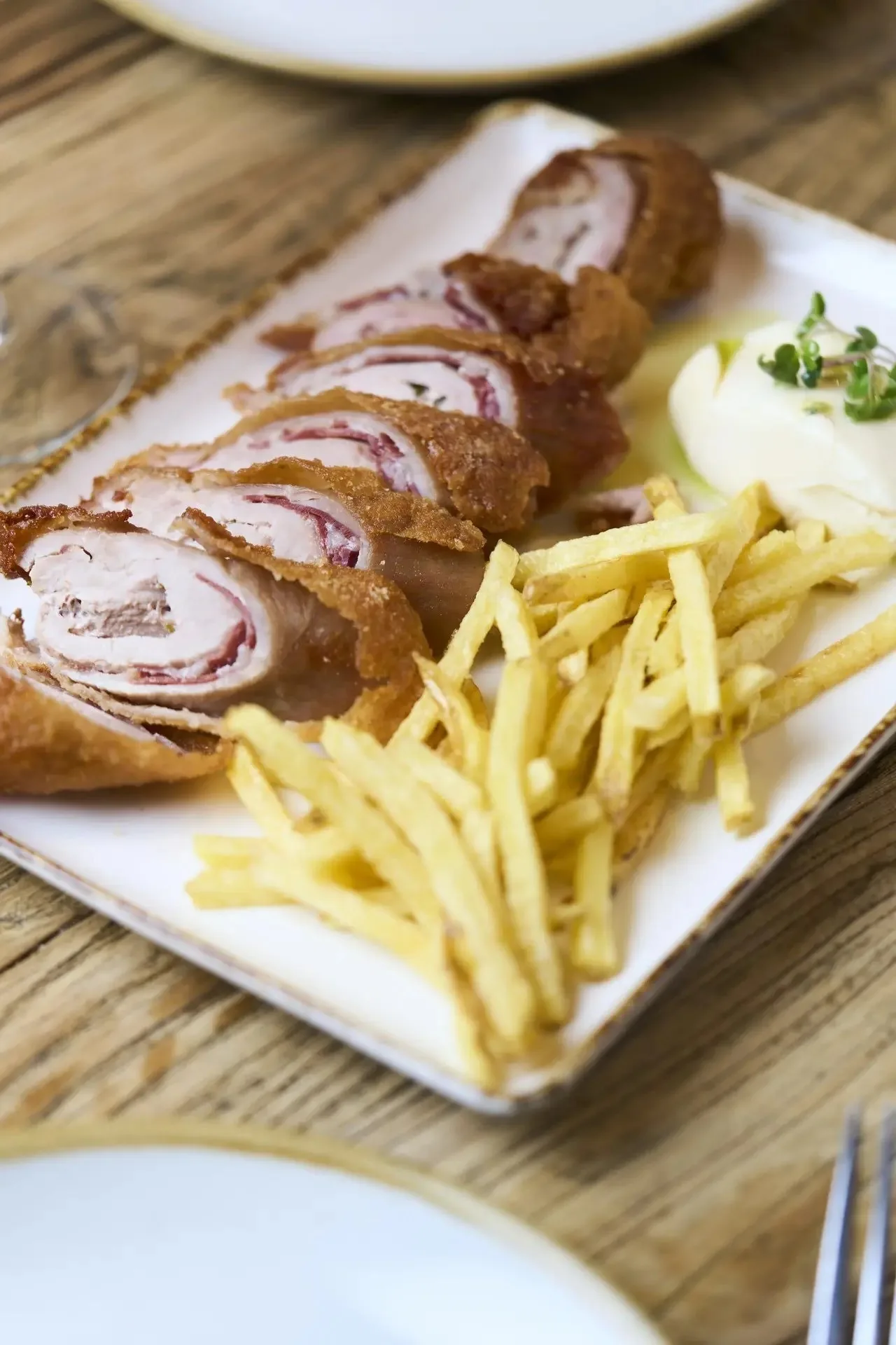 A sliced breaded roll with fries on a white plate