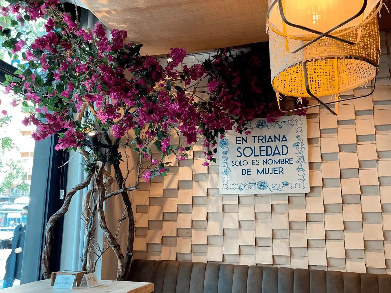 A wall of pink flowers and a blue and white tile plaque above a bench