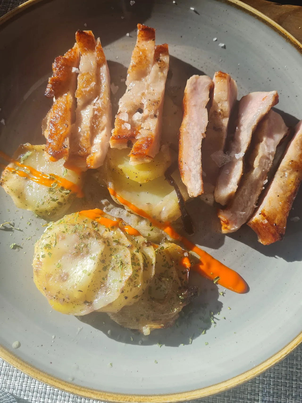 Sliced grilled meat served with roasted potatoes and a carrot garnish