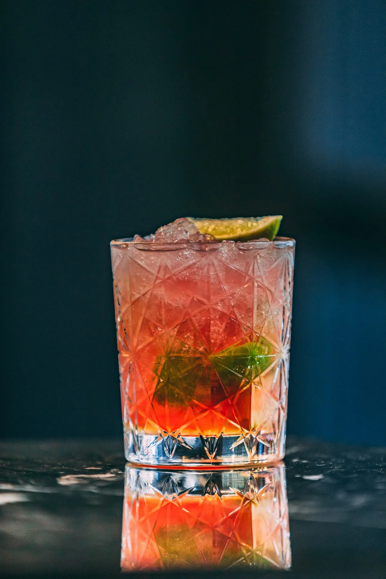 A red cocktail garnished with mint and citrus rind