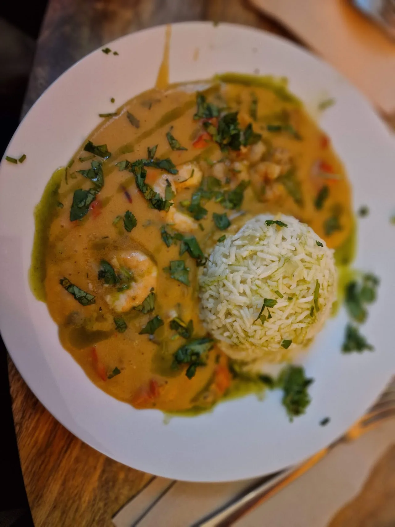 A bowl of coconut curry soup with shrimp and rice