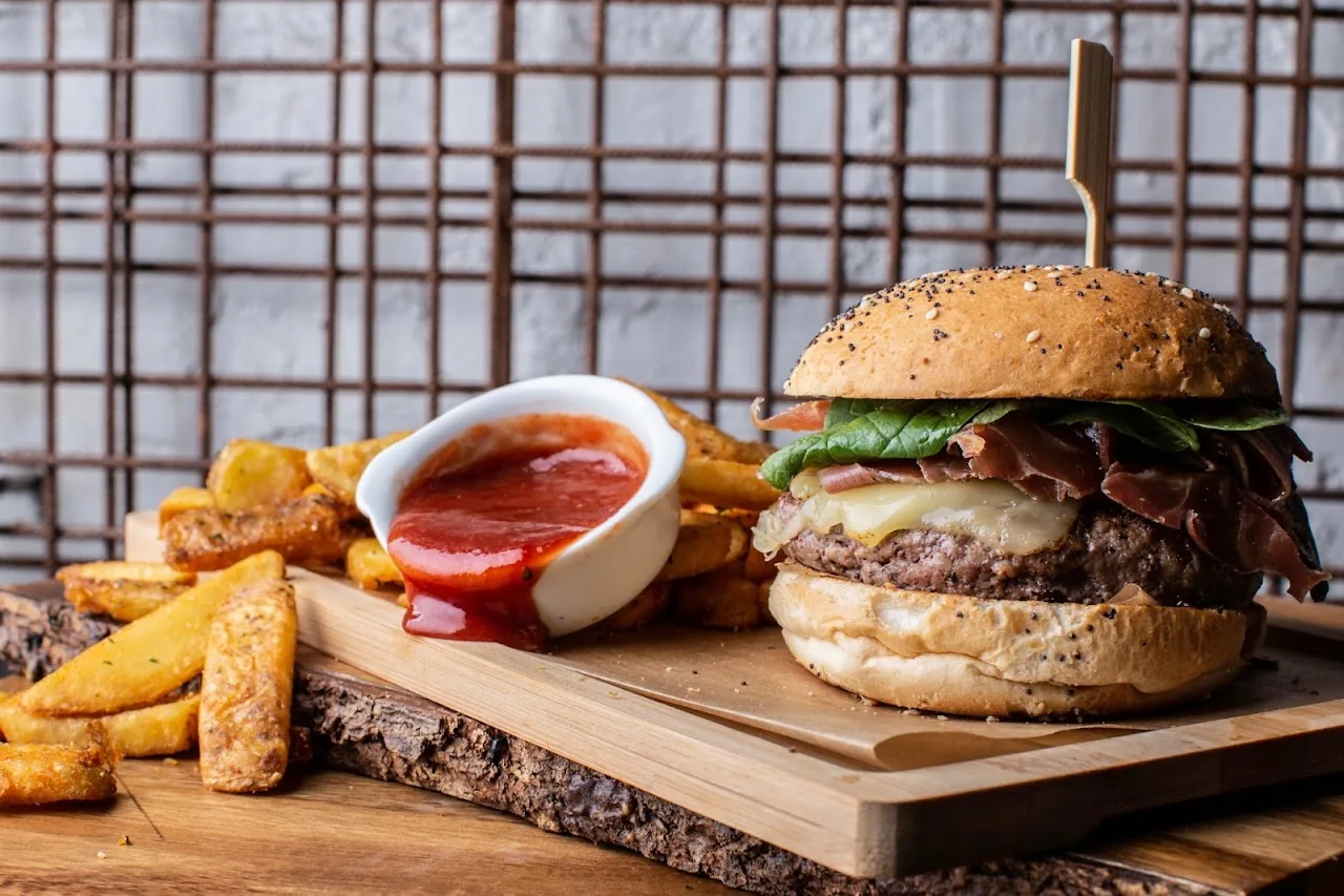 A burger with bacon and toppings served with fries and dipping sauces