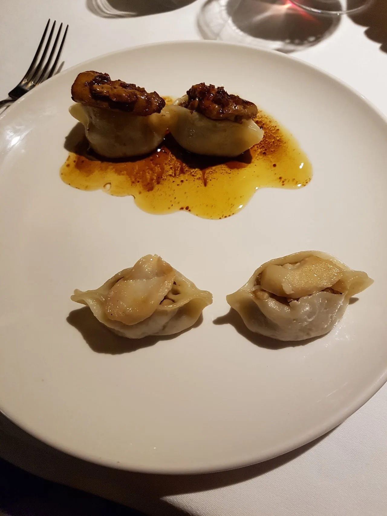 A plate with pan-seared scallops and two dumplings