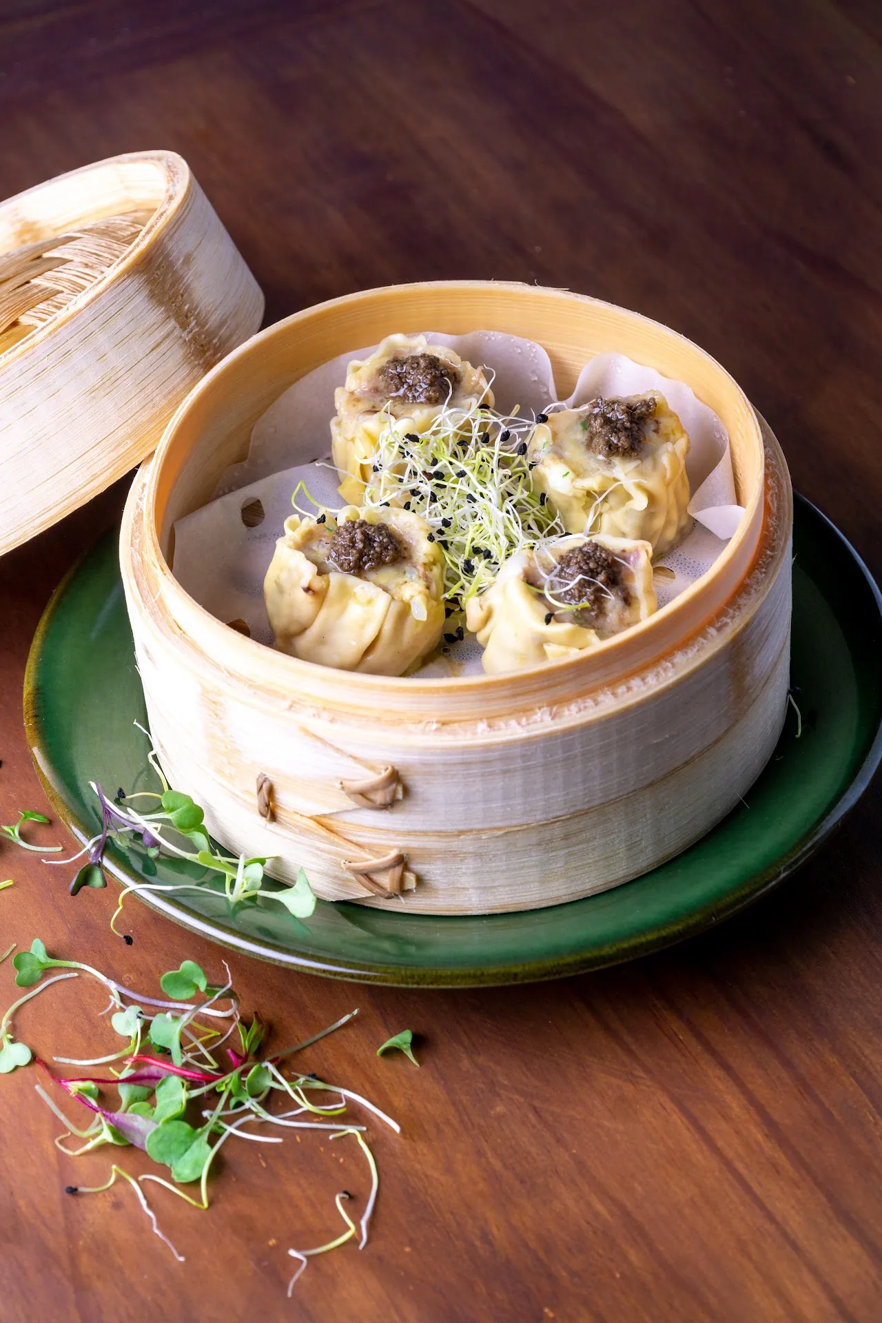A bamboo steamer of dumplings with microgreens