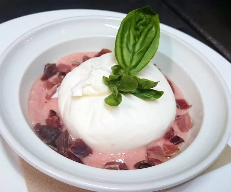 A ball of burrata on a bed of diced beets with a basil garnish.