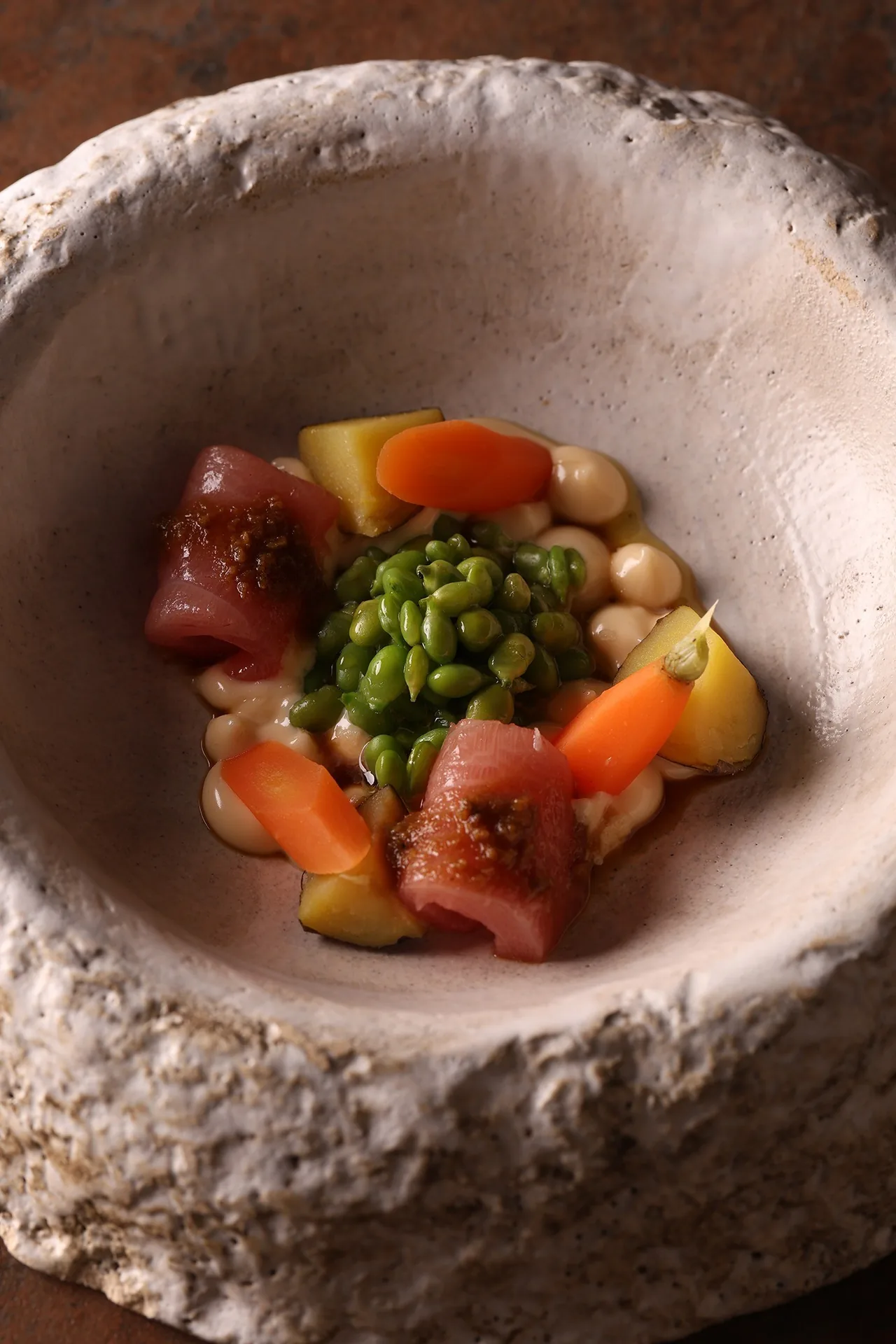 A textured bowl of diced red fish with green peas and diced vegetables