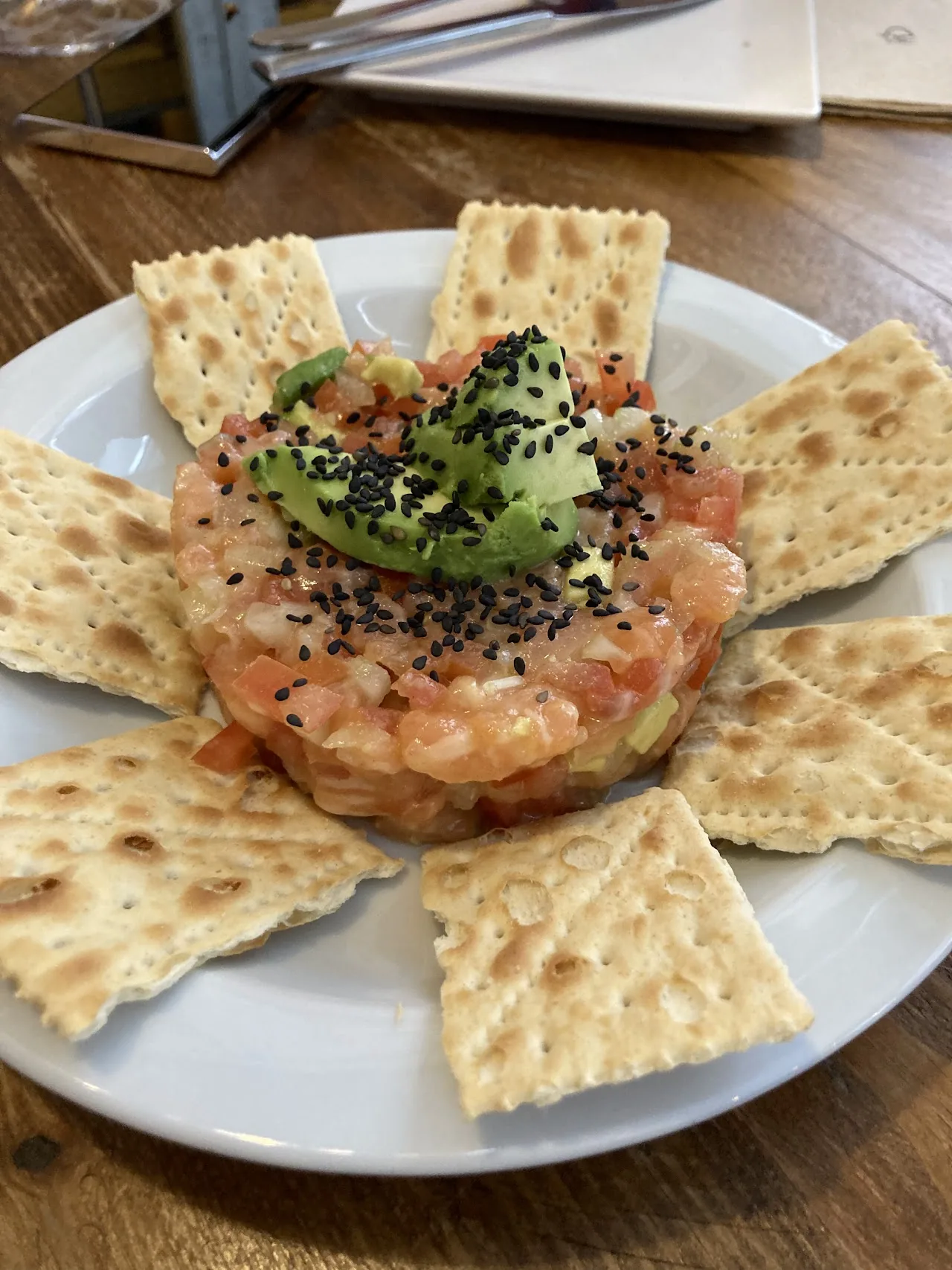 A tuna tartare with avocado and sesame seeds, served with crackers