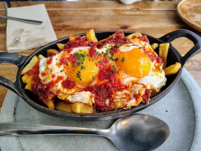 A skillet of fries topped with fried eggs and paprika