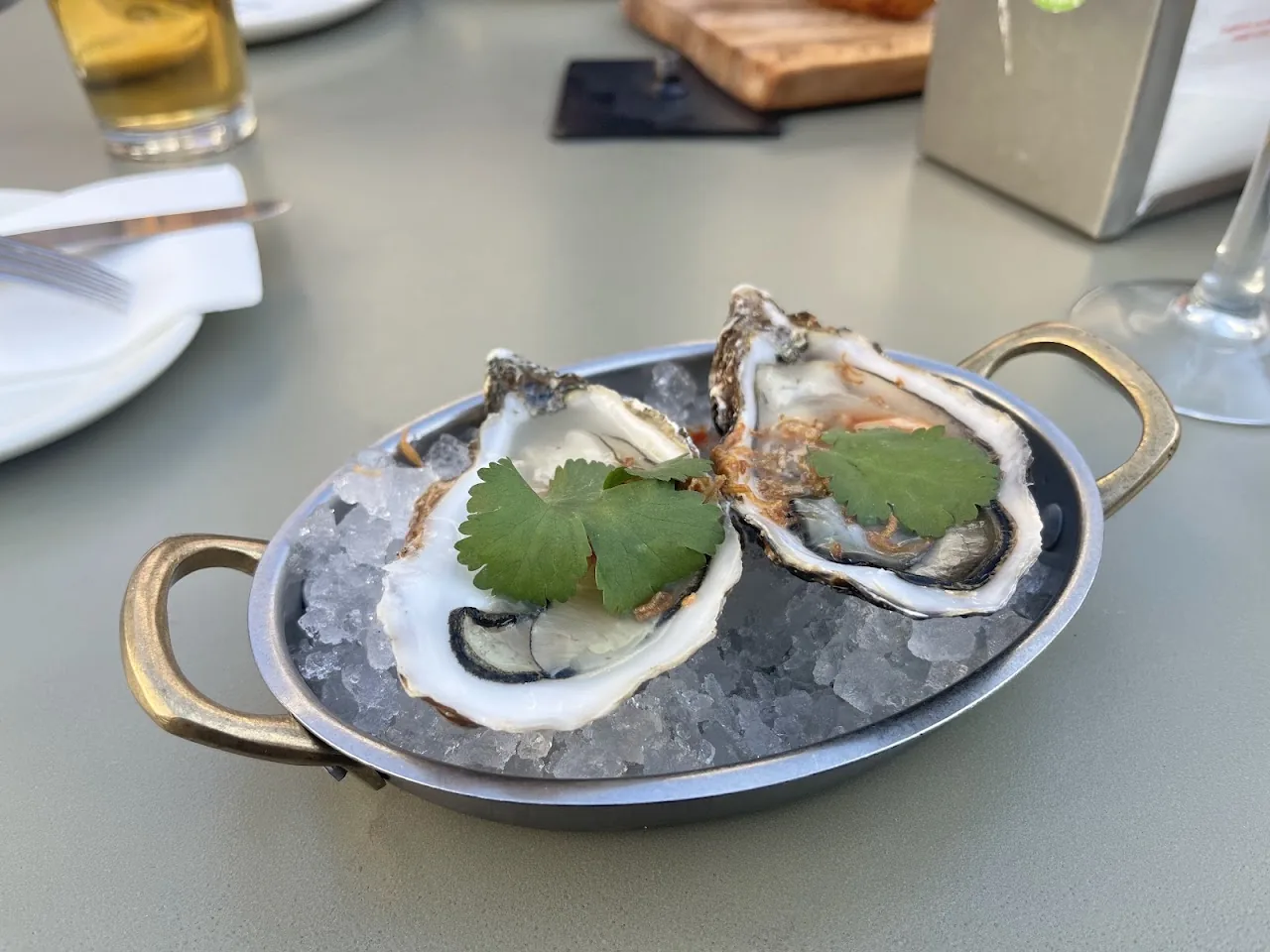 Two oysters served on a bed of ice with mint garnish
