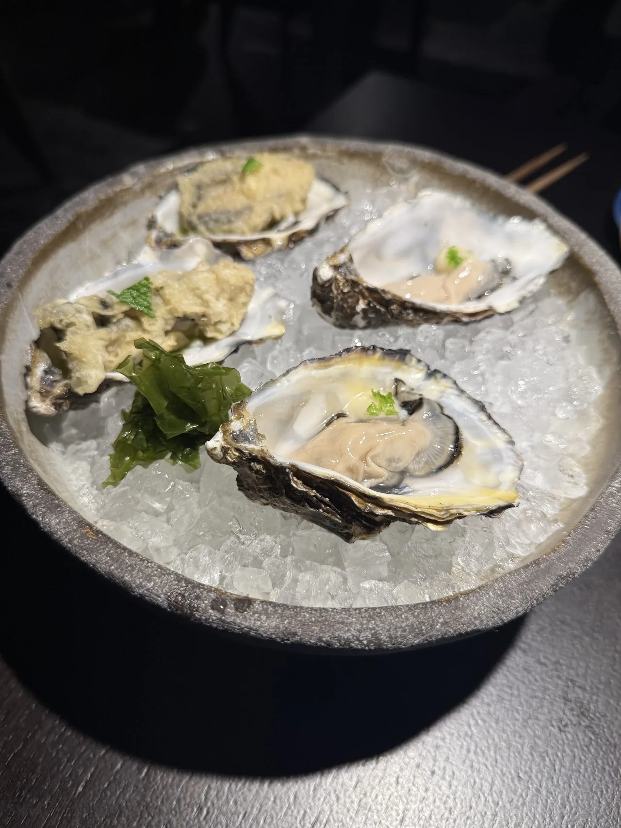 Four oysters on the half shell served on ice with a fresh herb garnish