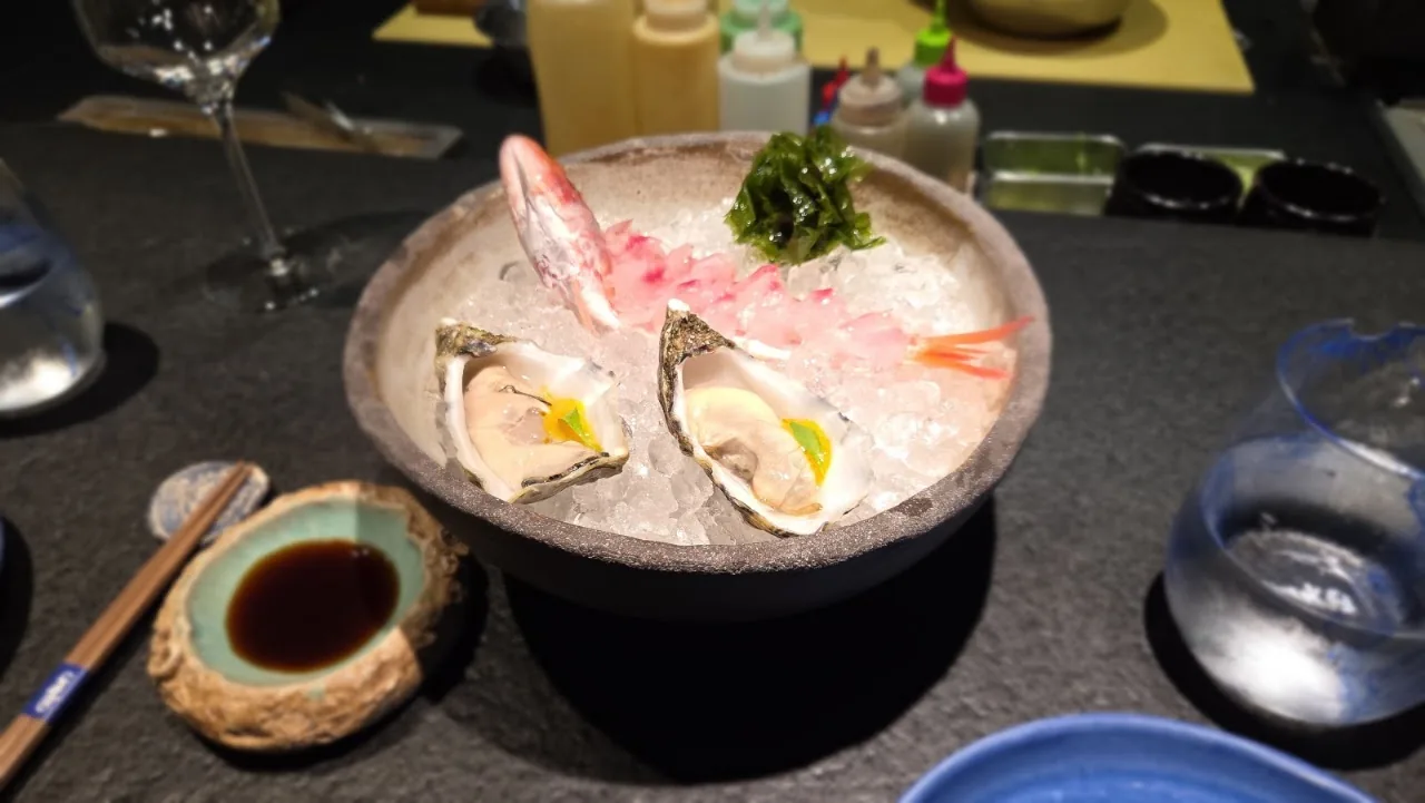 A chilled seafood platter with oysters, shrimp, and citrus on ice