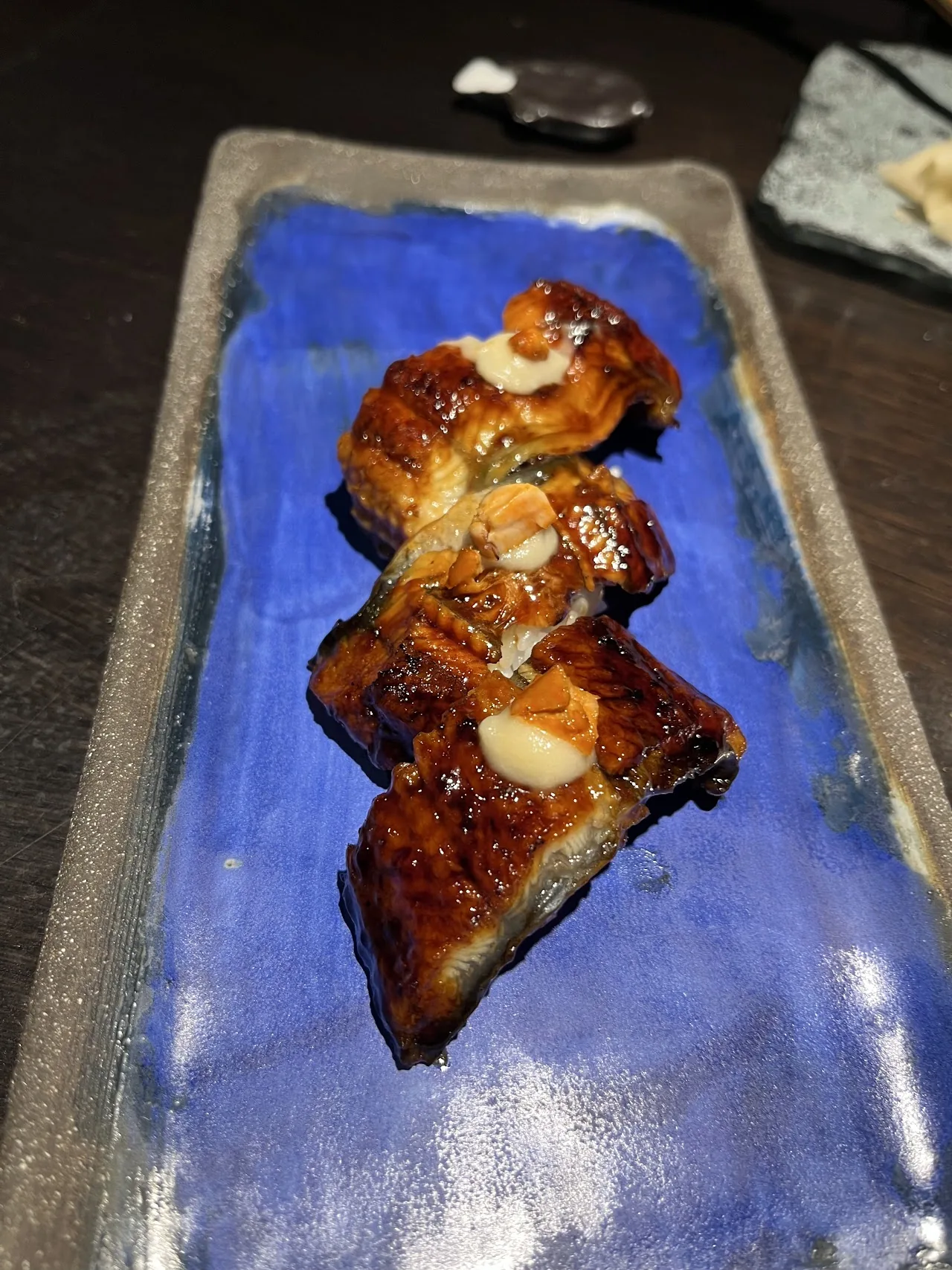 Grilled eel fillets glazed and sliced, served on a blue plate