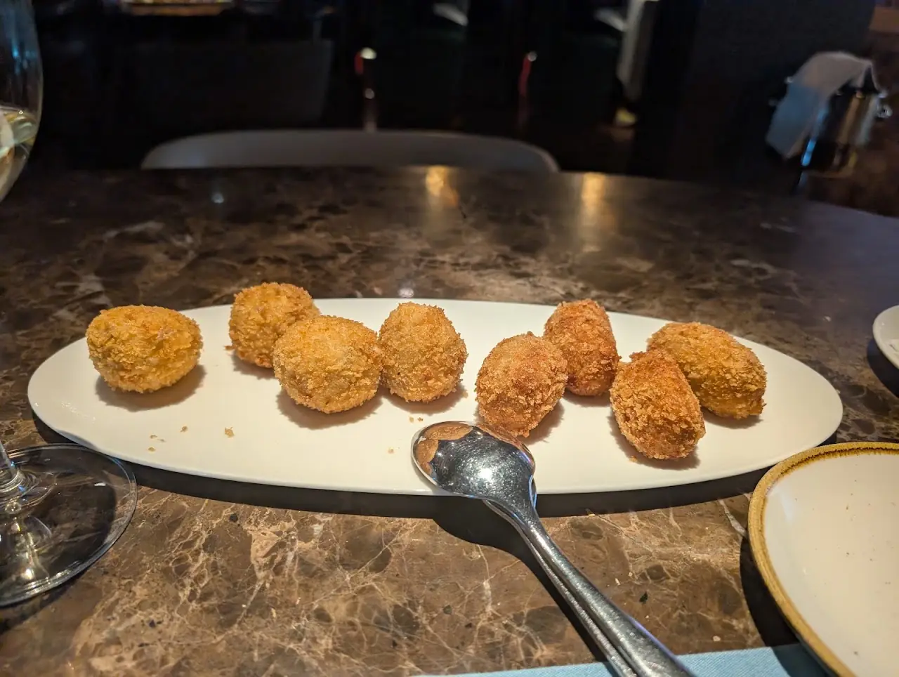 Breaded and fried croquettes lined up on an oval plate.