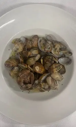 Sautéed clams in garlic and parsley sauce on a white plate at Urretxu