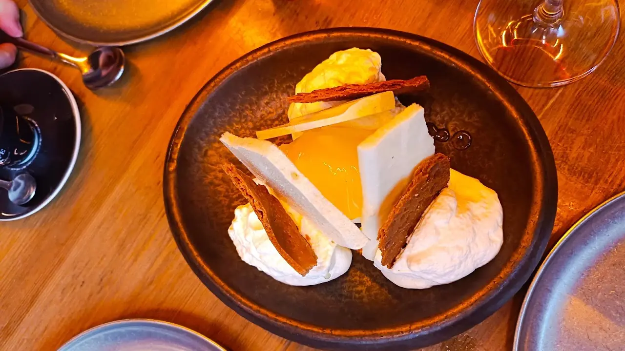 A wedge of creamy dessert with a golden sauce, whipped cream and a cinnamon stick