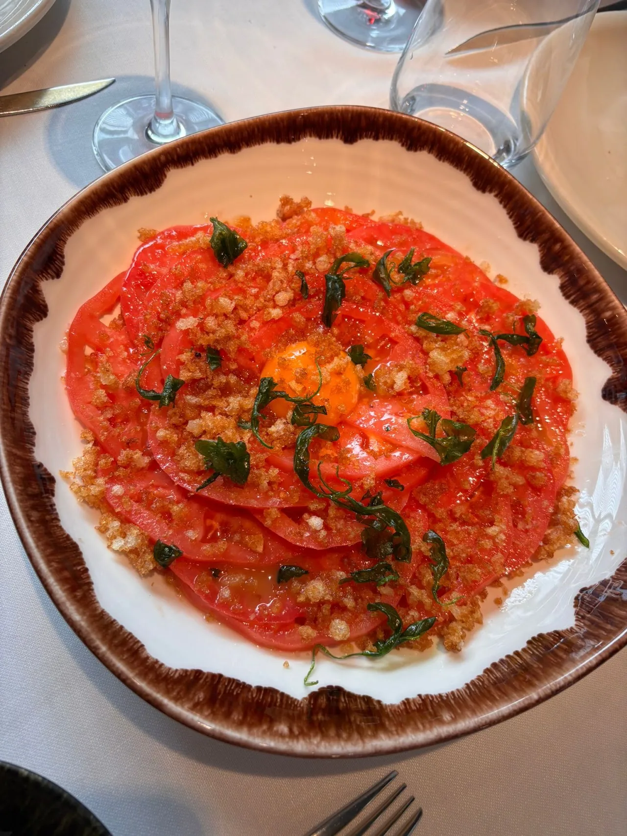 A plate of sliced tomatoes with olive oil and herbs