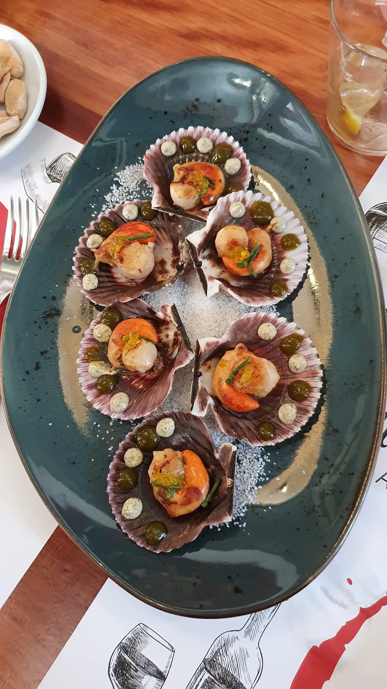 Clams on the half shell plated on a dark oval dish.