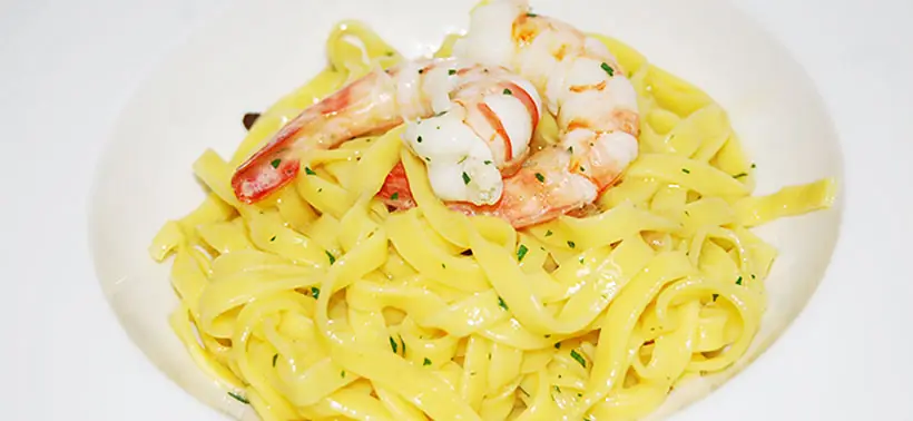 Tagliatelle pasta topped with two grilled prawns and chopped parsley, at Valentin Restaurant Xarcuteria