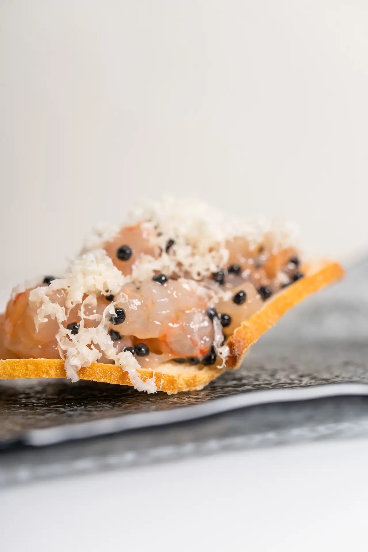 Crisp tuile topped with shrimp tartare, black caviar pearls and shaved cheese