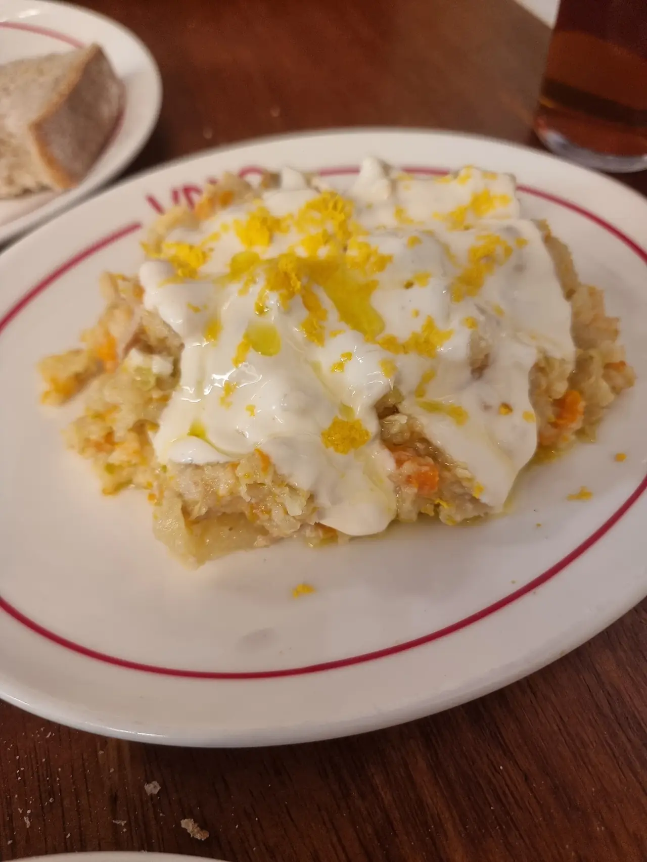 Ensaladilla topped with grated egg yolk on a white plate with a red rim