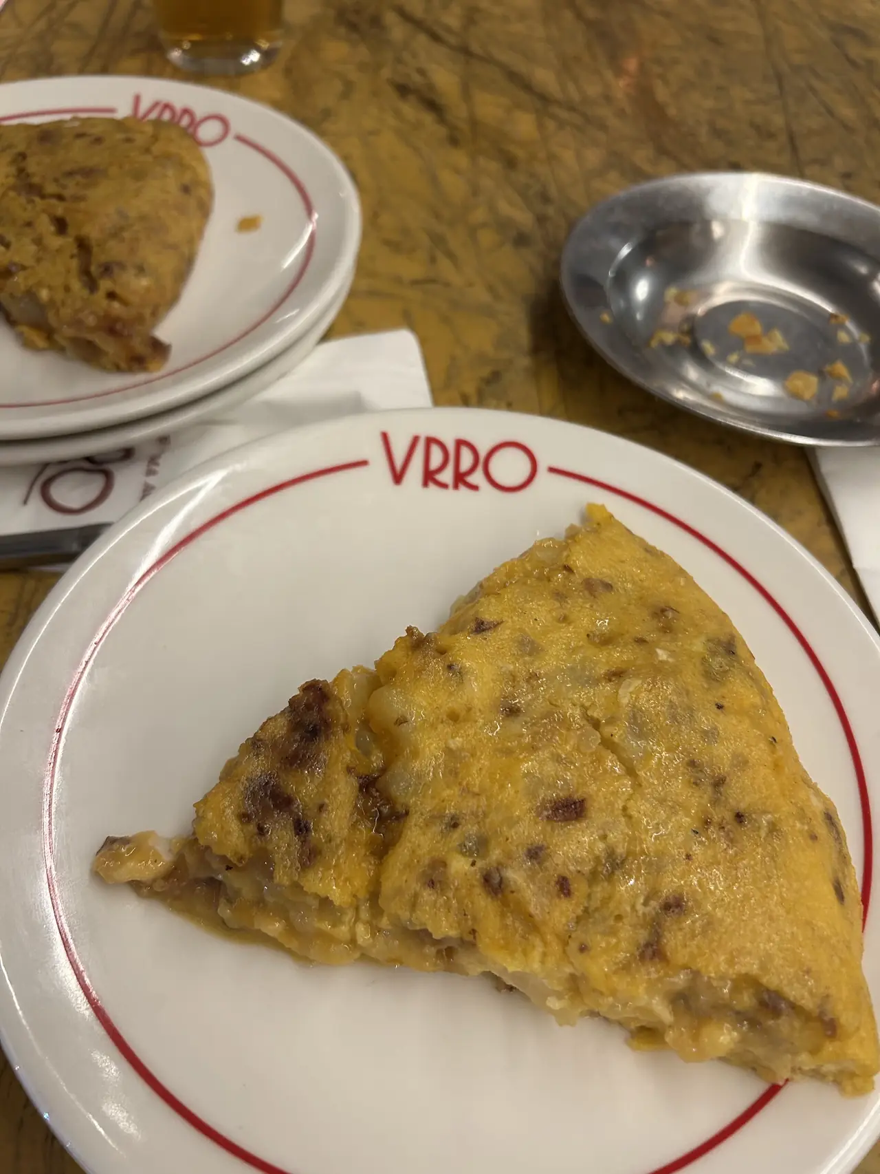 A wedge of tortilla de patata on a white plate with a red rim