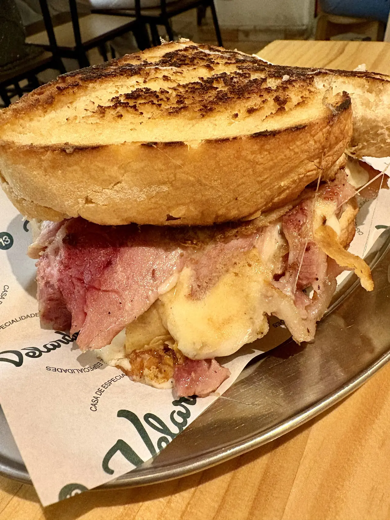 Close-up of toasted sandwich with roast beef and melted cheese on branded paper