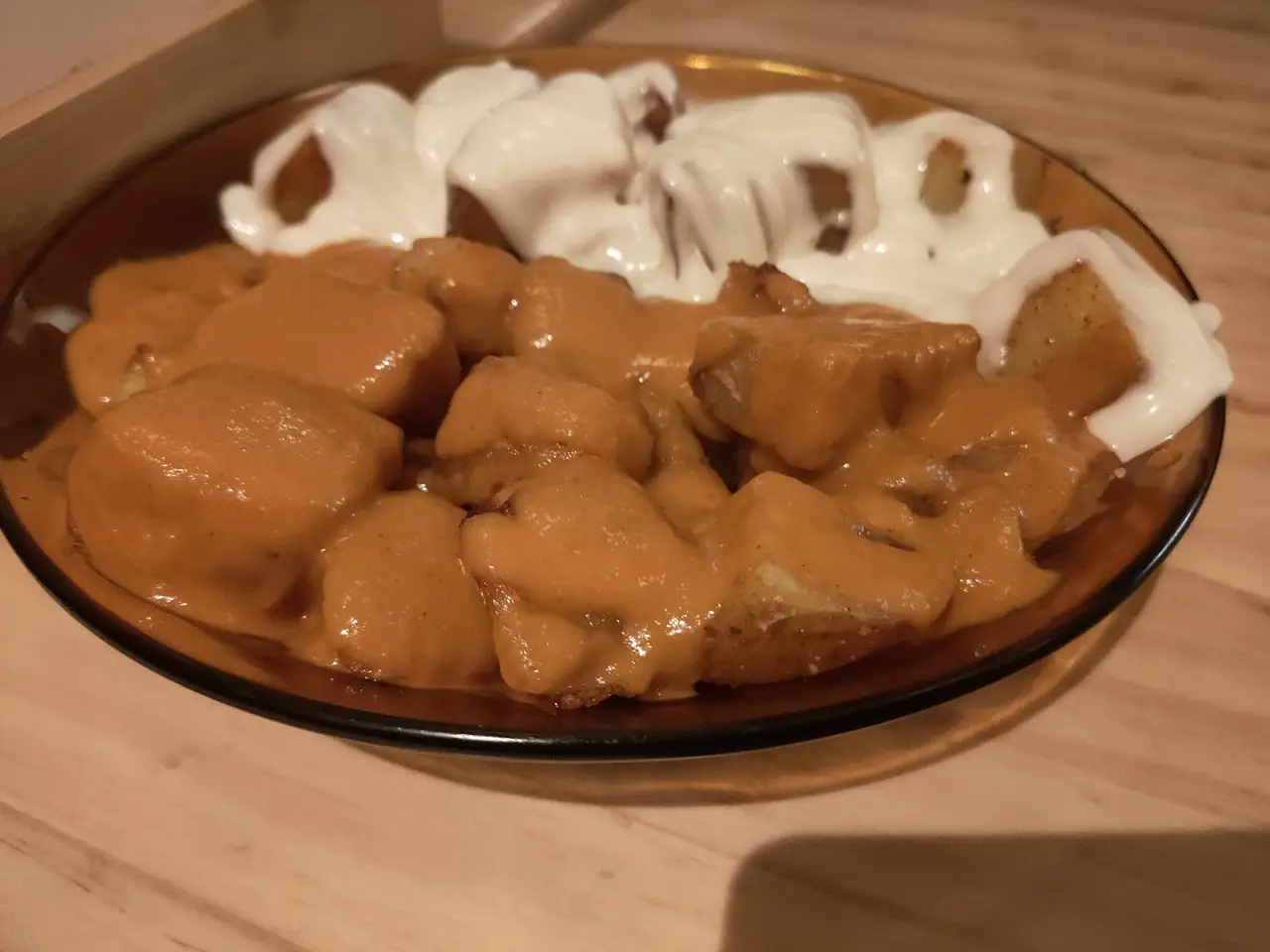 Patatas bravas topped with brava sauce and aioli on amber plate