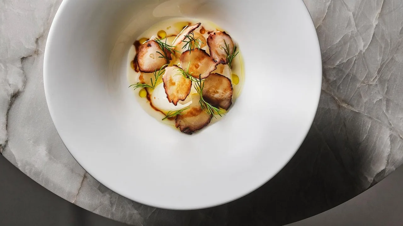 A white bowl of sliced mushrooms in a pale sauce with fine herbs