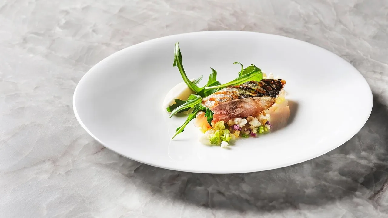 A fish dish with green garnish on a white oval plate