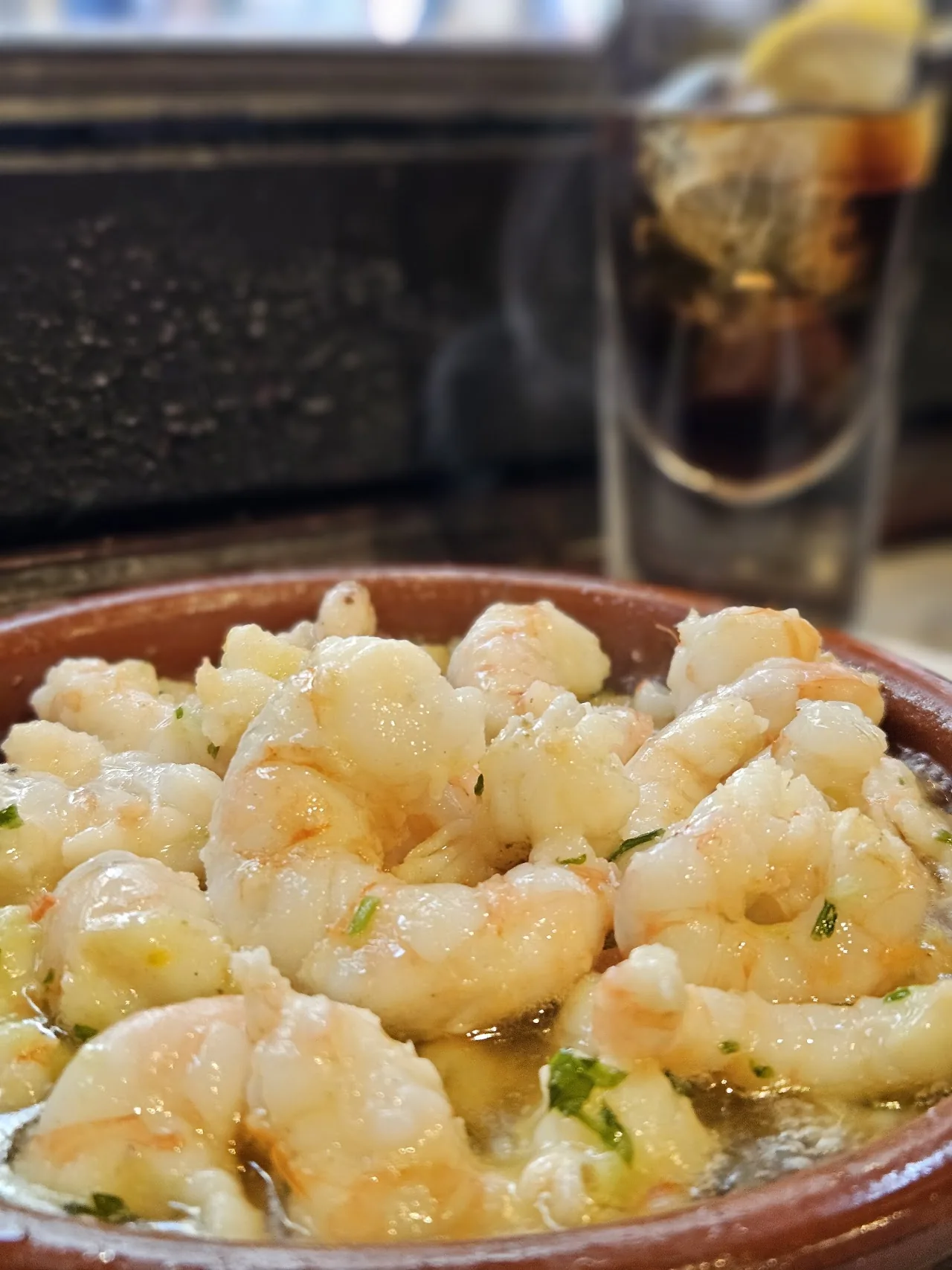 A bowl of garlic shrimp in oil with parsley