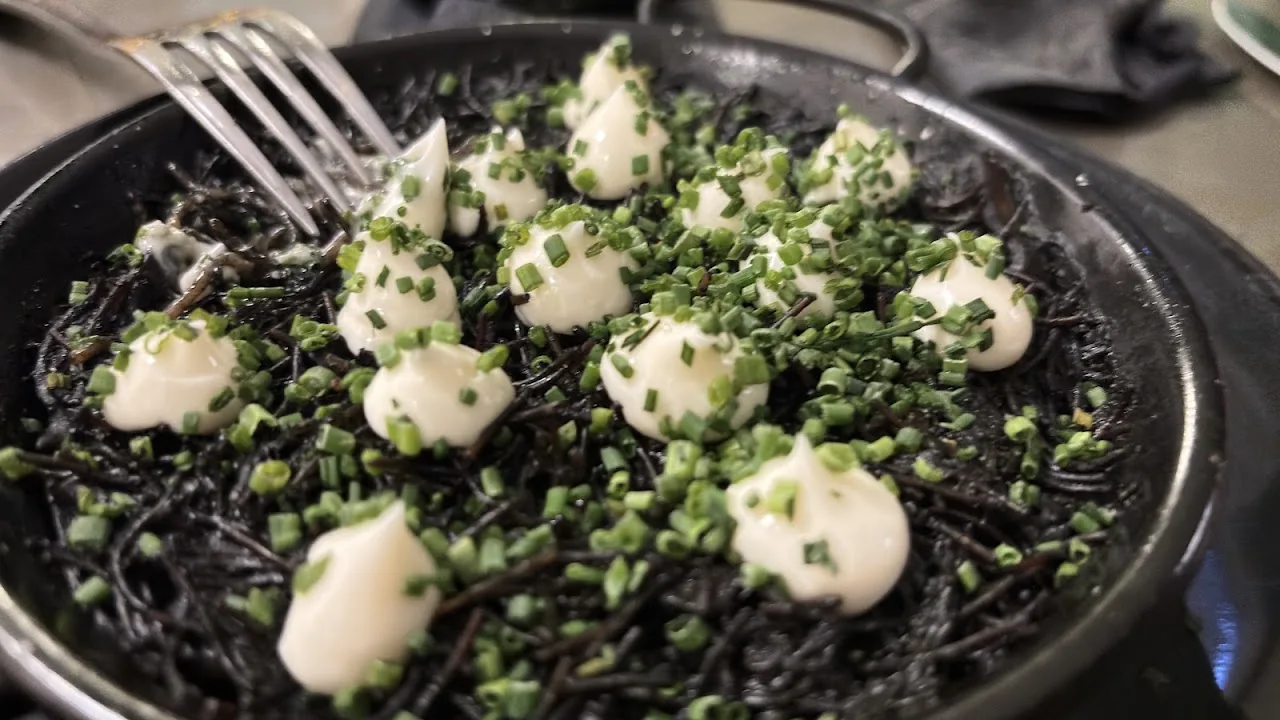 Black squid-ink pasta topped with dollops of cream and herbs