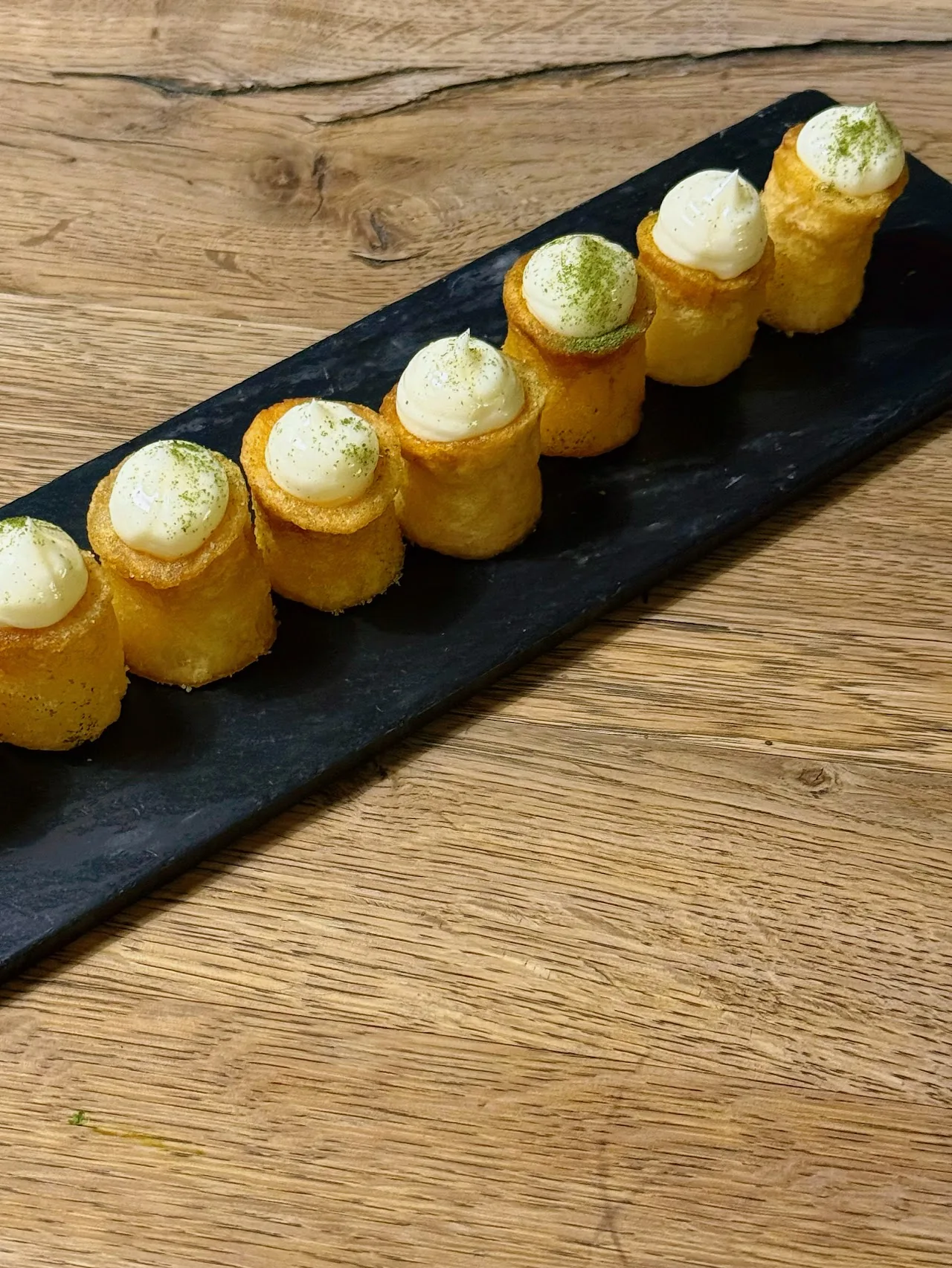 A row of crispy canapes topped with cream and herbs